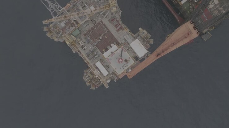 Drone footage of a crane working above an oil rig offshore