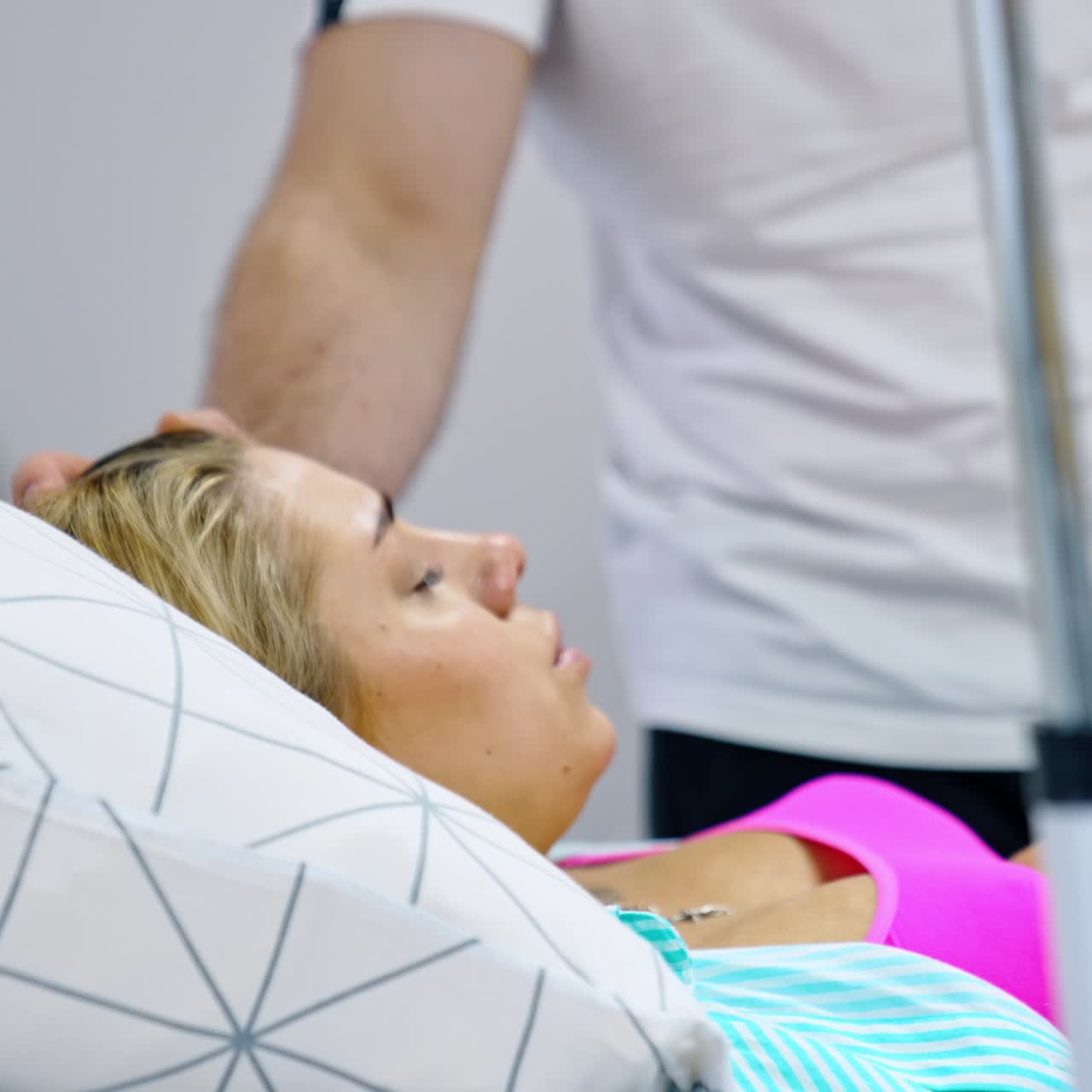 Loving man stands at the bed of his pregnant wife. Blonde lady breathing deep to relief painful contractions