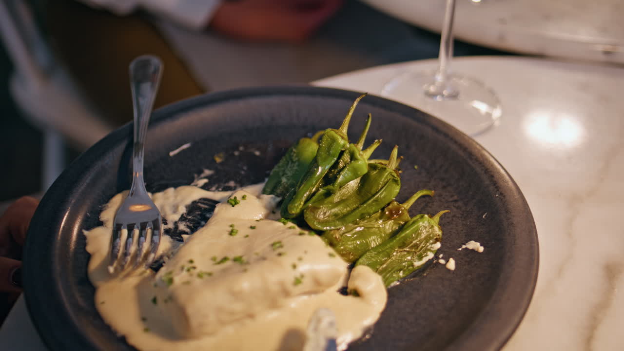 Gourmet vegetarian dish served with peppers on black plate closeup. Person hand