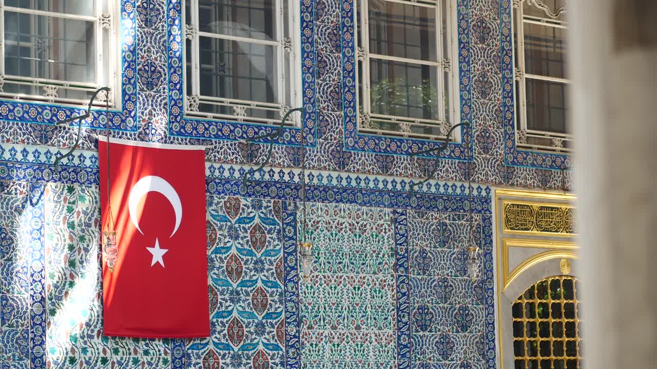 Drapeau turc flottant sur un bâtiment orné de carreaux islamiques