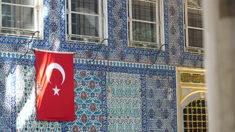 turkish flag hanging on a building with islamic tiles