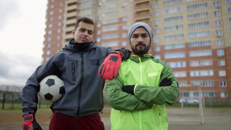 selbstbewusste männliche fußballspieler, die auf dem feld posieren und in die kamera schauen