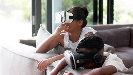 happy african american brother and sister in vr headsets on sofa, slow motion