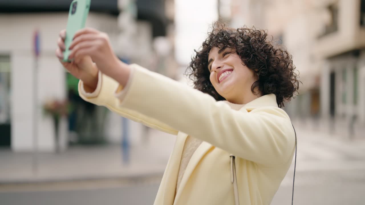 Young woman smiling confident making selfie by the smartphone at street