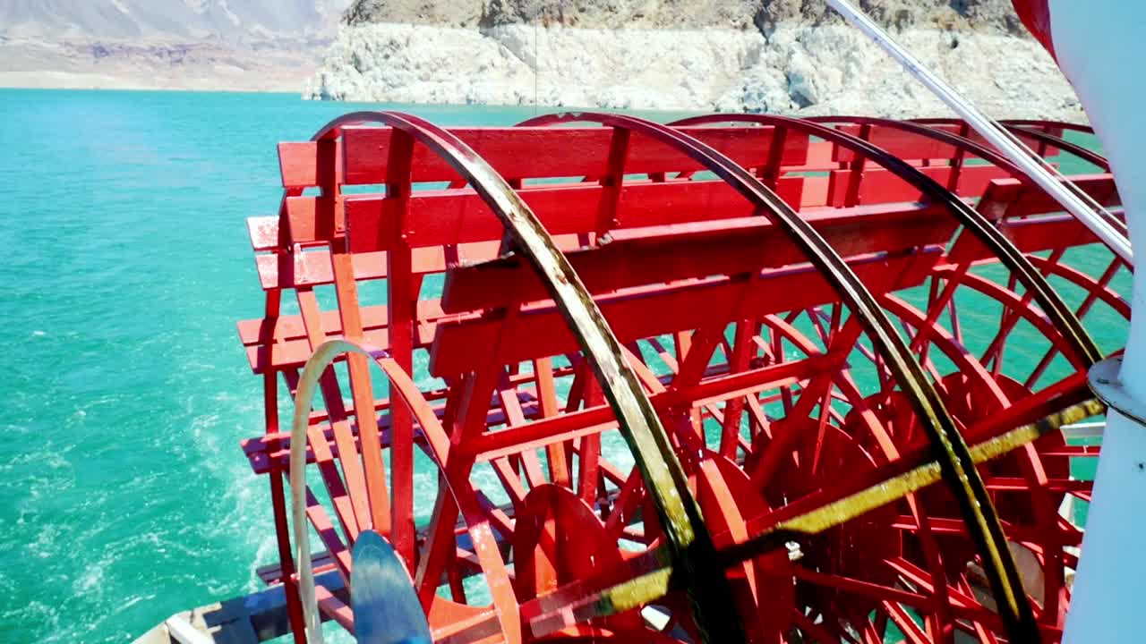 Red paddle wheel rotating on a paddle steam boat on a lake