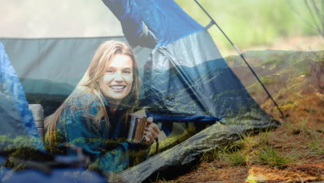 smiling woman holding mug in tent over scenic mountain landscape