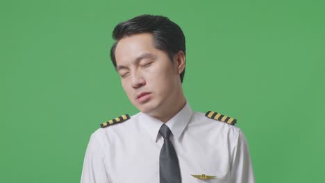 close up of asian man pilot wiping the sweat and being tired while standing in the green screen background studio