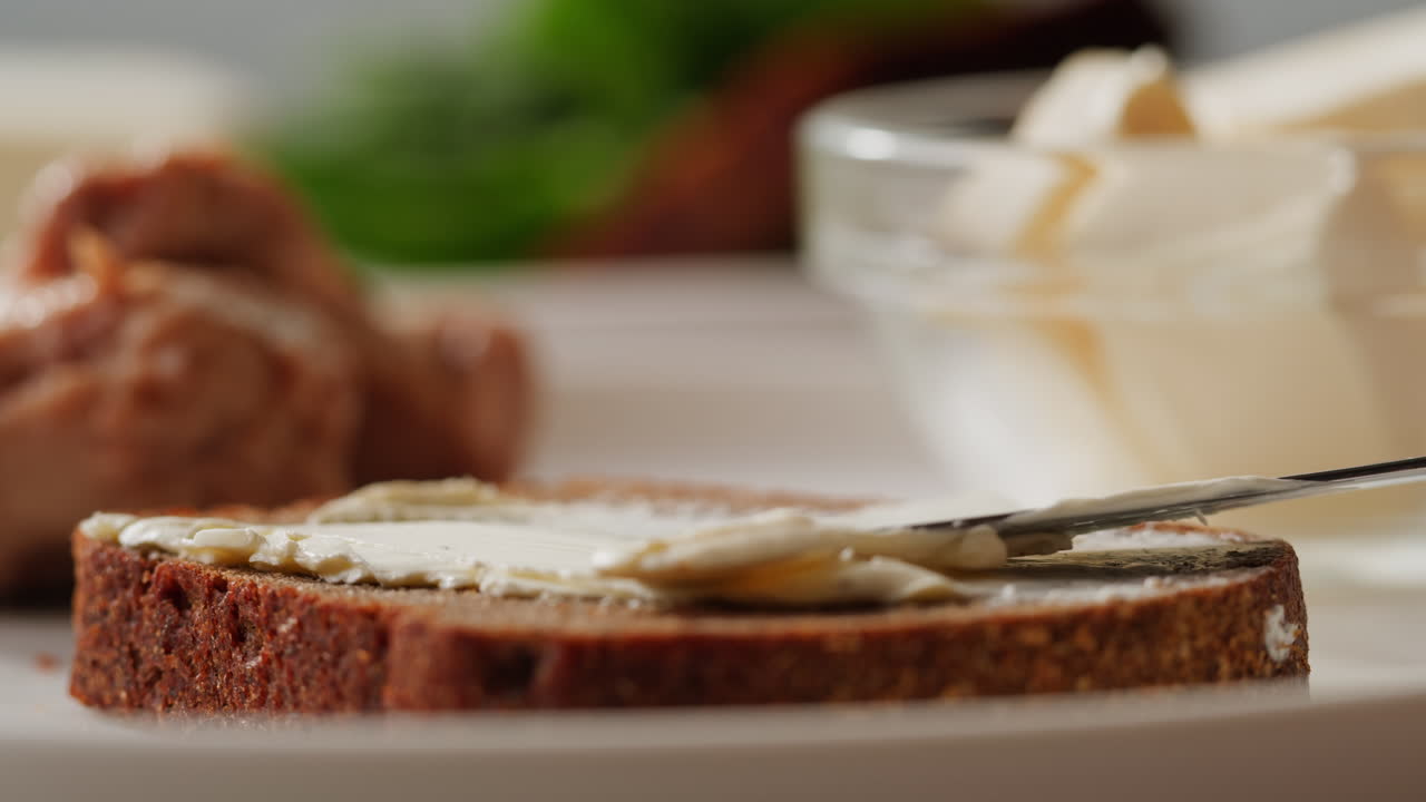 Young woman spreading nut butter onto toast in kitchen, closeup. High quality 4k footage