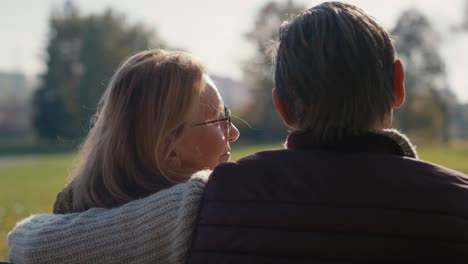 Senior-caucasian-couple-sitting-and-embracing-together-in-park