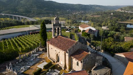 Iglesia-Santa-Maria-de-Fea-in-Toen-Ourense-Galicia-Spain,-golden-hour-light-on-facade-and-grassy-cemetery