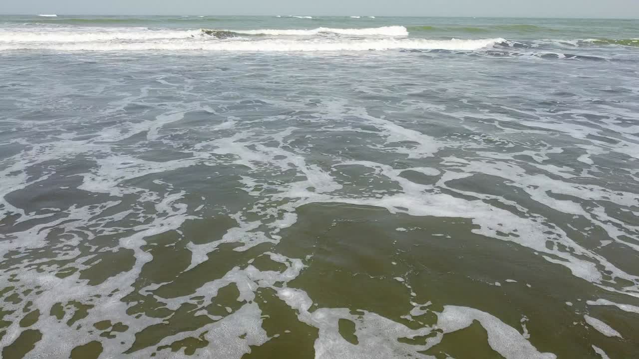 Lavtflyvende over bølger som ruller inn mot strendene ved Cape Point, Bakau - Gambia