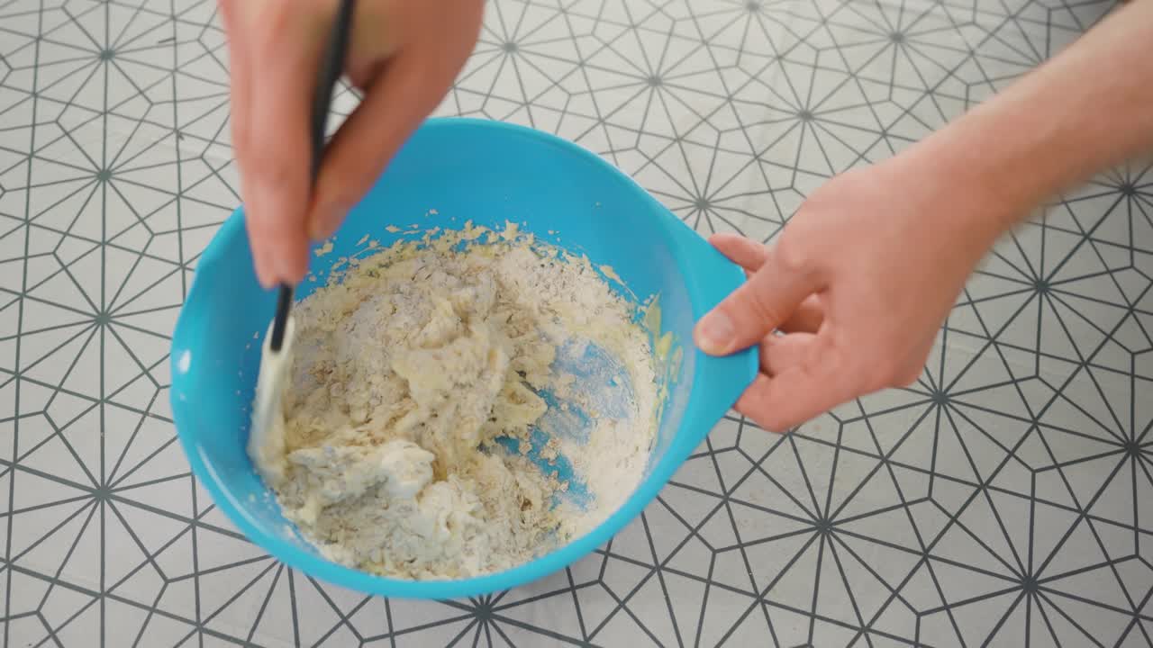 hombre combinando los ingredientes para la masa de pastel en un tazón azul