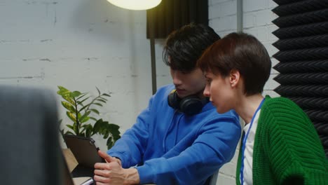 a man and woman work sitting at one work desk in a office