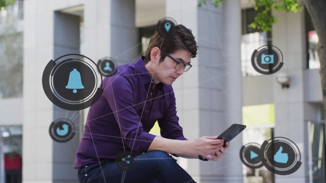 animación de iconos de redes sociales sobre hombre asiático usando tableta al aire libre