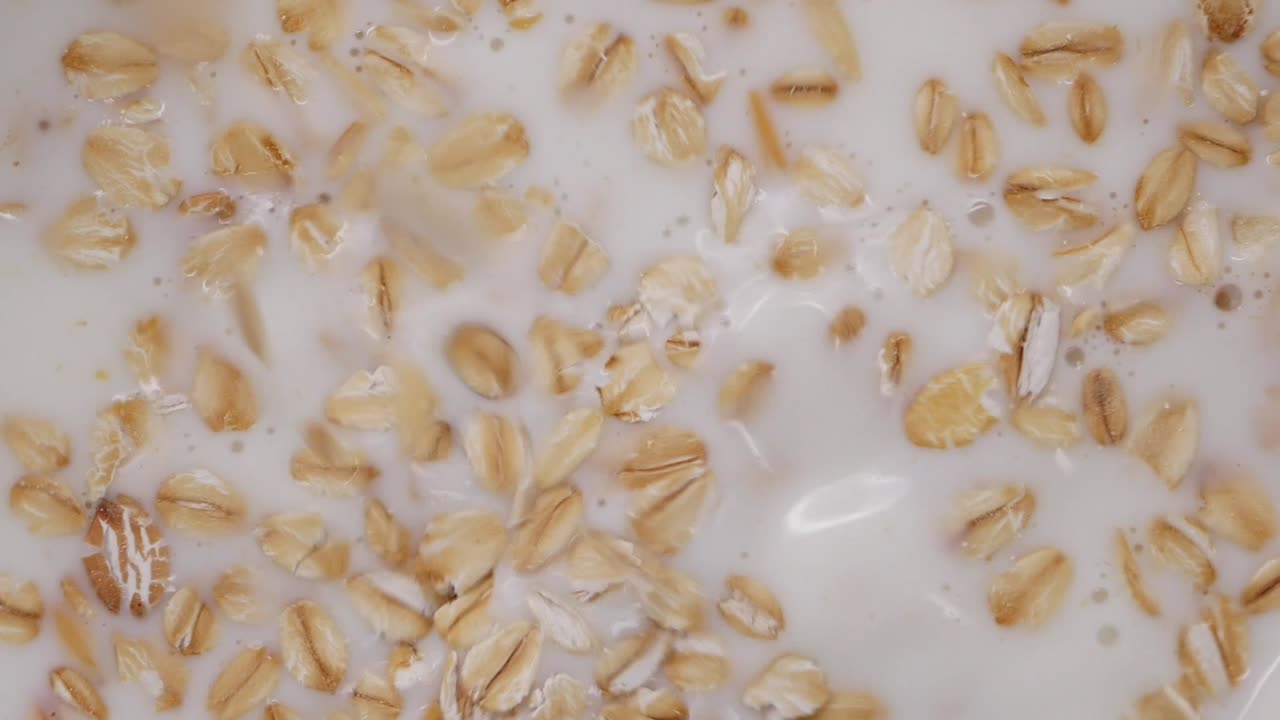 Versamento al rallentatore di avena e frutta secca nel latte