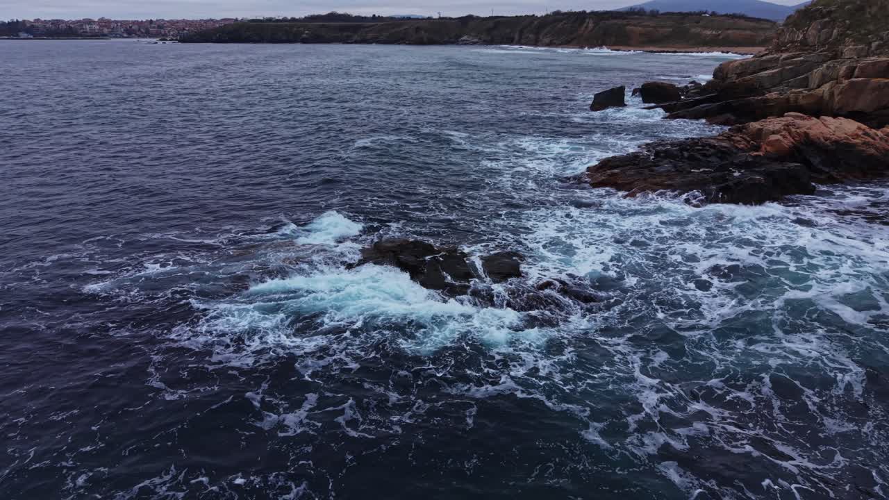 Waves crash against rocky coast near water in coastal area