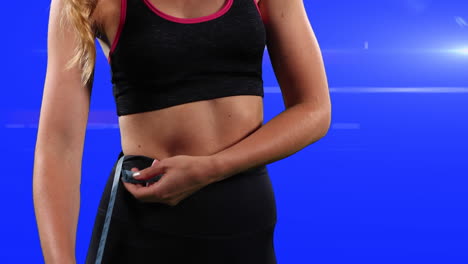 mujer caucásica en traje deportivo tomando sus medidas en un fondo azul con rayos blancos