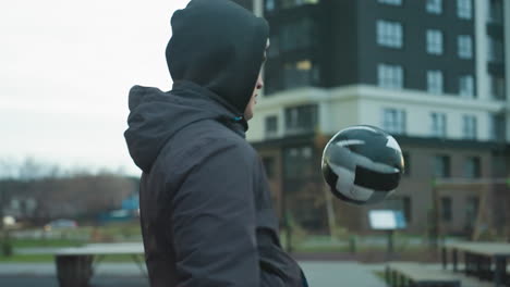 close-up of athlete juggling soccer ball during training in urban sport arena, demonstrating focus and skill against blurred background of modern buildings and people walking in the distance