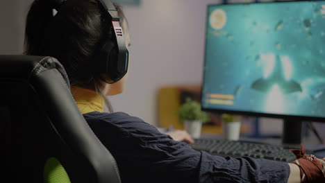 focused woman gamer sitting on desk putting on headset