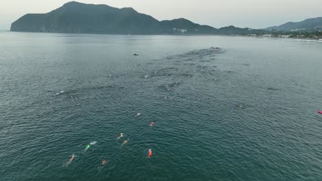 swimmers racing in the ocean during triathlon contest in the early morning