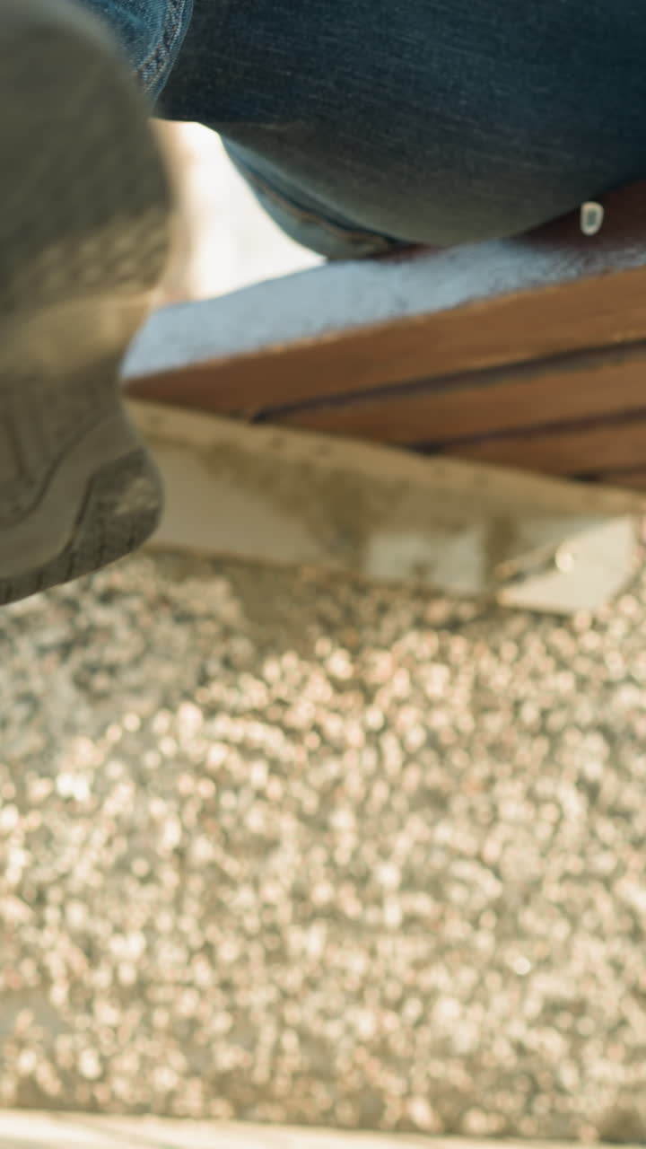 primer plano de un adulto y un niño sentados juntos en un banco, el niño cuelga las piernas jugosamente, tocando suavemente las piernas cruzadas del adulto, con un fondo borroso de árboles