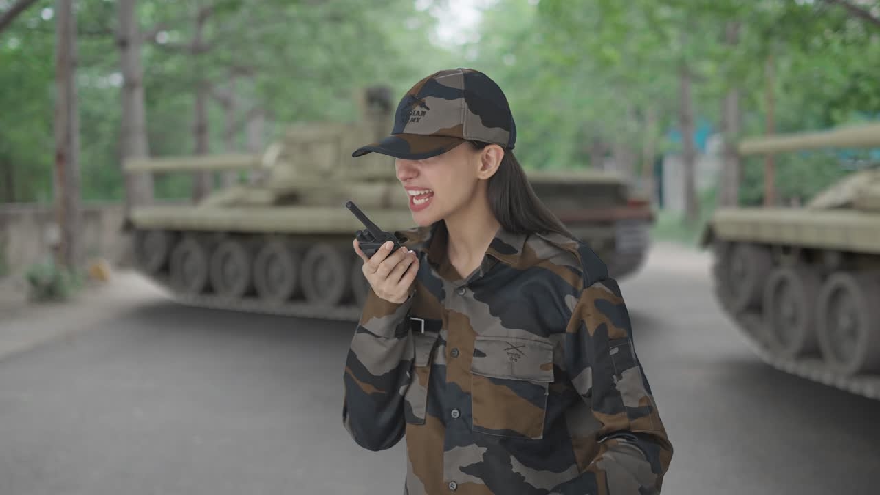una mujer india enojada, oficial del ejército, gritando por walkie talkie.