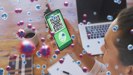 Digitale-Komposition-Von-Covid-19-Zellen-über-Einer-Frau,-Die-Ein-Smartphone-Mit-QR-Code-Auf-Dem-Bildschirm-Hält