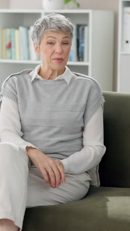 a woman with gray hair is sitting on a couch and talking to someone.