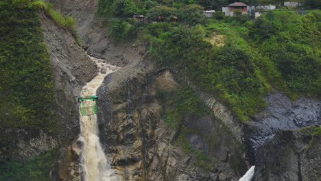 slow motion shot of gigantic waterfall and cable car with small village in jungle mountains of ecuador