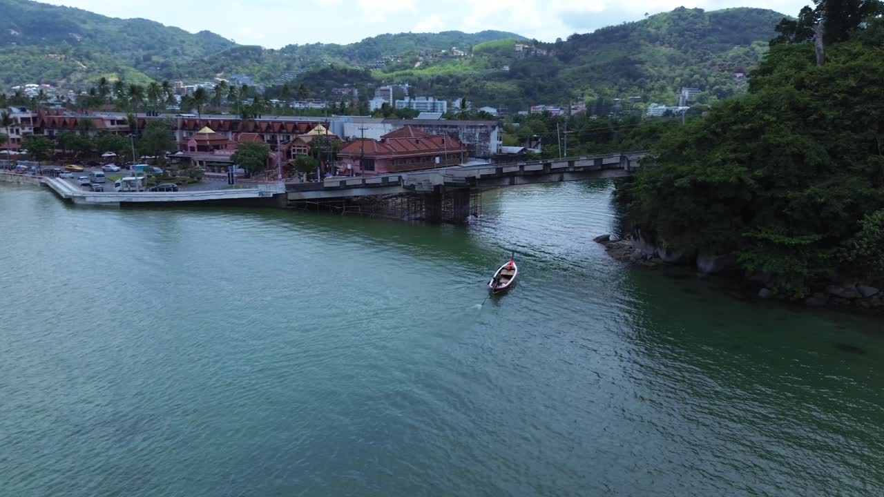 Vista aerea di un ponte a Patong circondato da un paesaggio tropicale che include montagne, foreste, la costa, edifici urbani e barche longtail, creando una vista panoramica diversificata a Phuket, Thailandia.