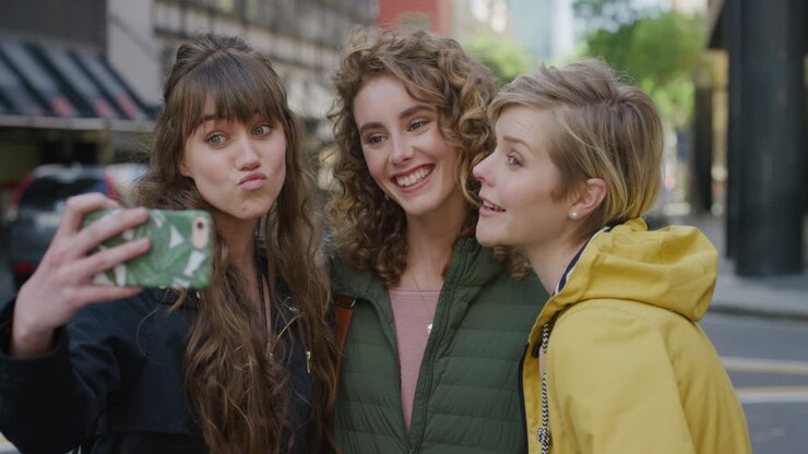 gruppo di amici donne che usano lo smartphone che posano sorridendo prendendo una foto selfie con la fotocamera del cellulare amiche che fanno facce divertendosi insieme