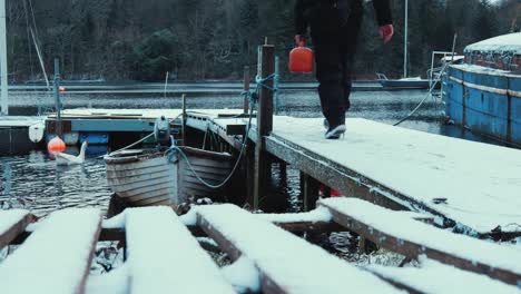 walking down pier with petrol for boat in snow