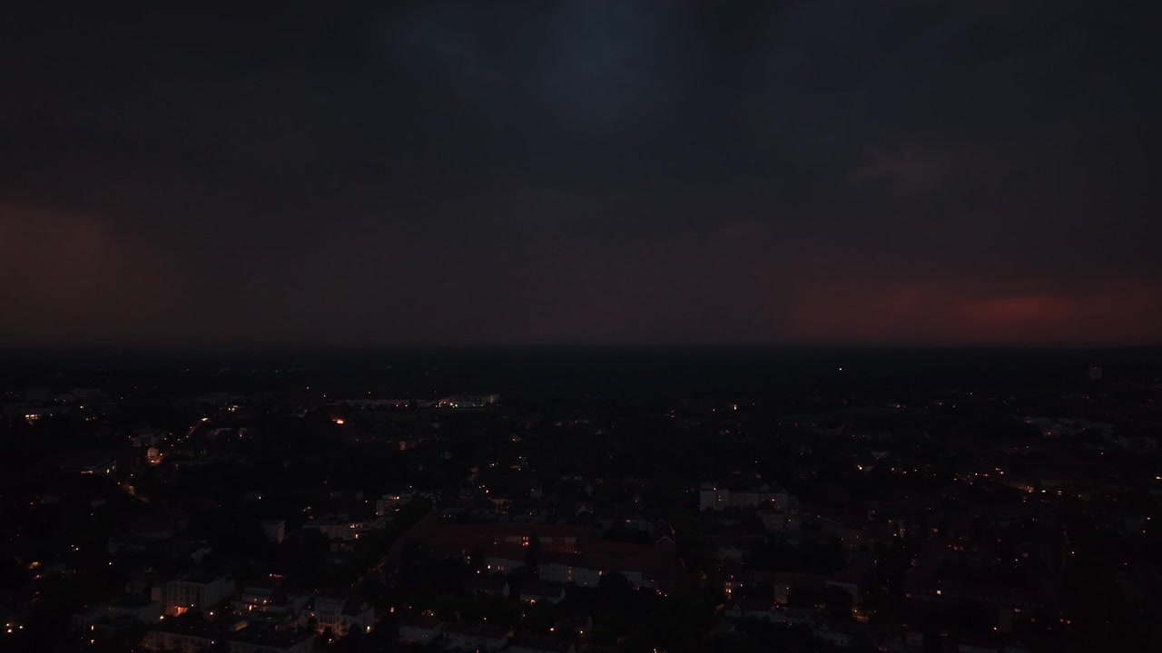 Lampo che illumina nuvole temporalesche scure sopra le luci della città di Berlino, mostrando fenomeni meteorologici drammatici e la potenza della natura. Splendida vista aerea.