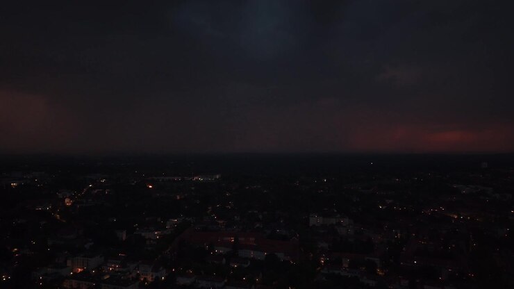 Lampo che illumina nuvole temporalesche scure sopra le luci della città di Berlino, mostrando fenomeni meteorologici drammatici e la potenza della natura. Splendida vista aerea.