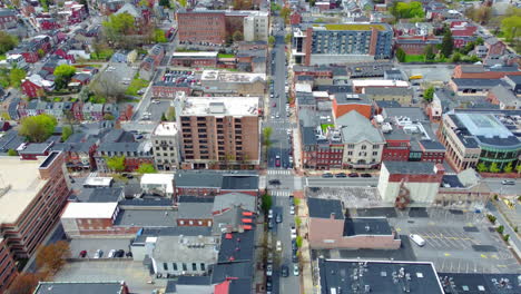 A drone glides directly above a main street in Lancaster City, PA, revealing a geometric grid of rooftops, crosswalks, traffic, and architecture—showcasing the vibrant rhythm of small-city life.