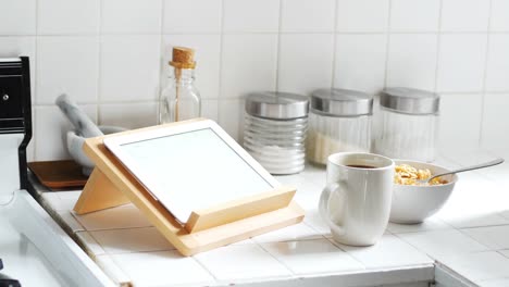 digital tablet and cup of coffee with breakfast bowl in kitchen 4k