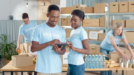 african american young male and female volunteers typing on tablet