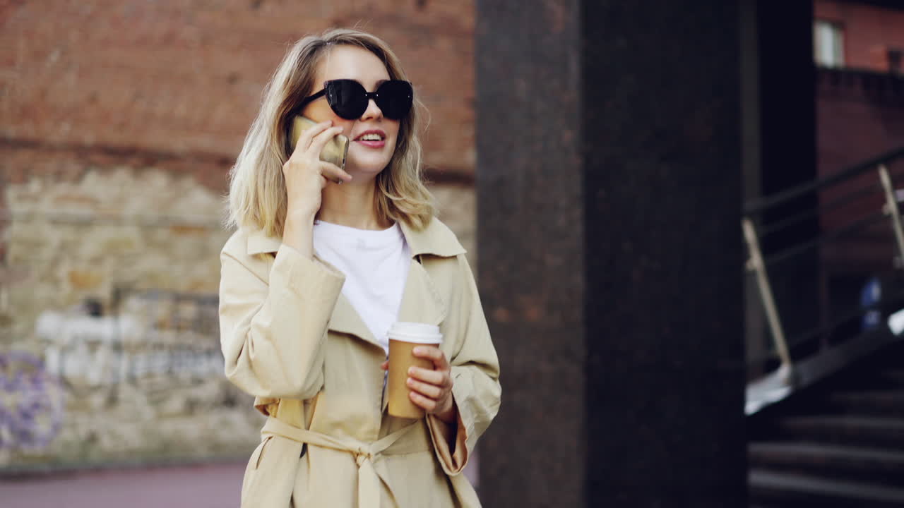 Woman walking in city, talking on phone, wearing trench coat
