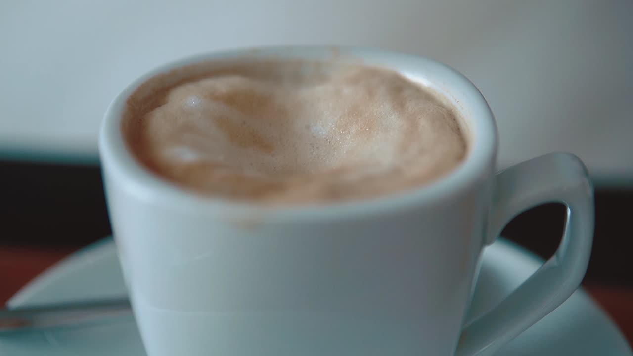 Sugar is poured into a mug of coffee then drowns in it in foam close-up