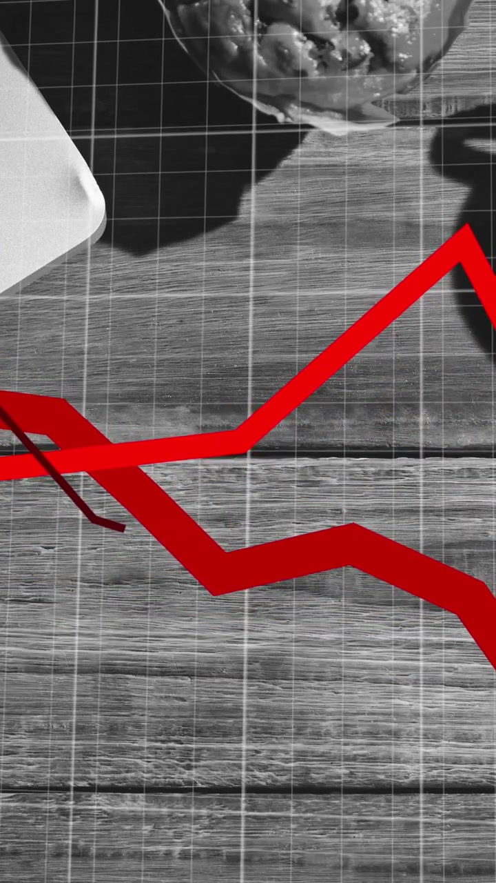 Red graphs moving over grid network against laptop and coffee cup on wooden surface