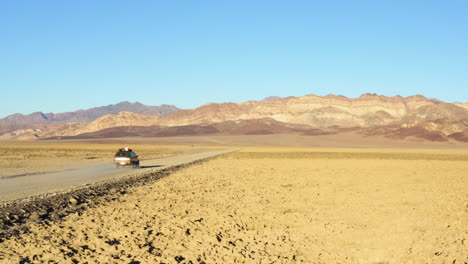 aerial view of suv jeep at high speed on road amidst vast endless barren terrain heading nowhere