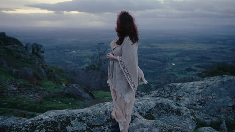mujer espiritual en la cima de una colina mirando el hermoso horizonte tiro largo