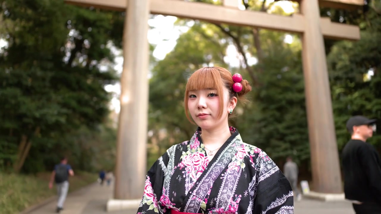 Una donna in yukata floreale sta davanti a un torii di legno a Tokyo.