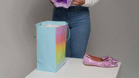 close up of female social media influencer producing user generated content taking beautiful pink shoes out of shopping bag 1