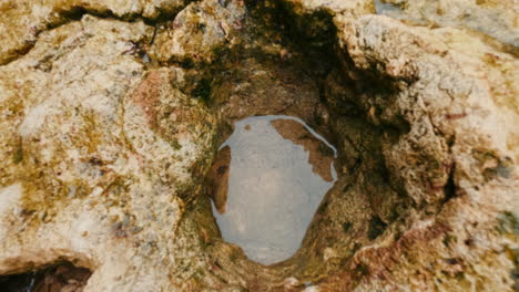 Cinematic-closeup-to-water-filled-hole-in-marine-rock,-Slomo,-120-FPS