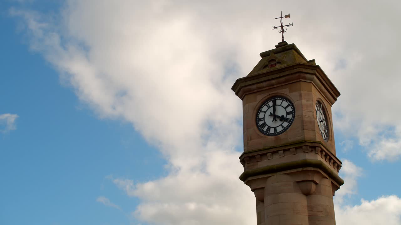 Timelapse de um relógio enquanto as nuvens passam no céu azul e claro ao fundo.