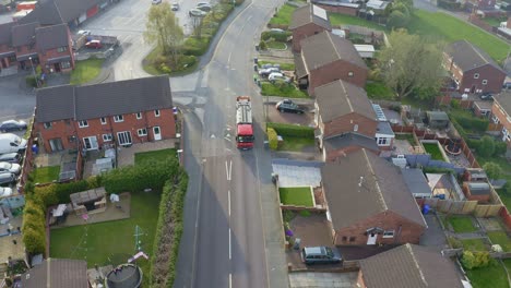 A-bin-lorry,-refuse-collection-vehicle-makes-it-way-up-the-road-as-men-load-recycling-bins-into-the-waste-compactor-in-a-middle-working-class-area-in-the-city