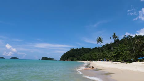 Slow-motion-footage-of-an-isolated-tropical-beach-with-two-attractive-women-sunbathing-in-bikinis-on-the-shoreline