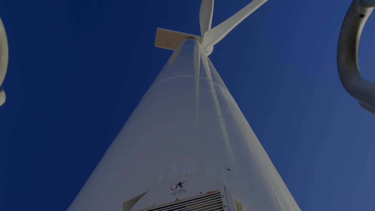 Technician pulling hatch handles at wind turbine, lowering panel for safety check with code overlay