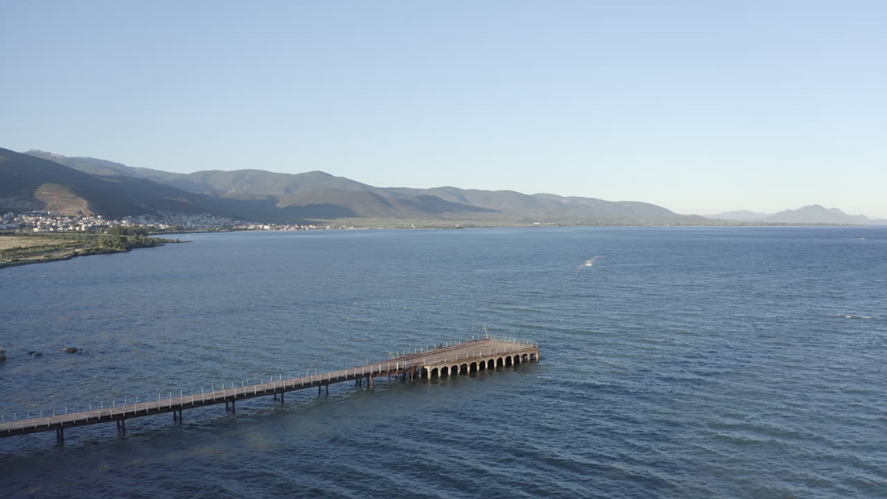 Empty concrete pier on ocean coast has old stone arch construction